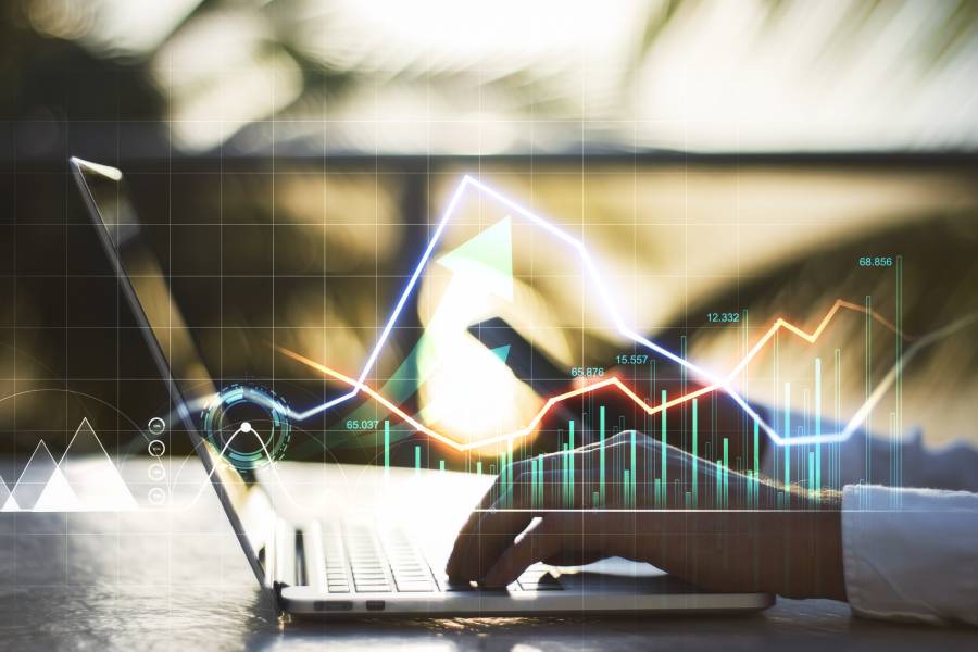 Persona trabajando en laptop con gráficos financieros digitales superpuestos, representando el análisis de datos en el proceso de conciliación financiera