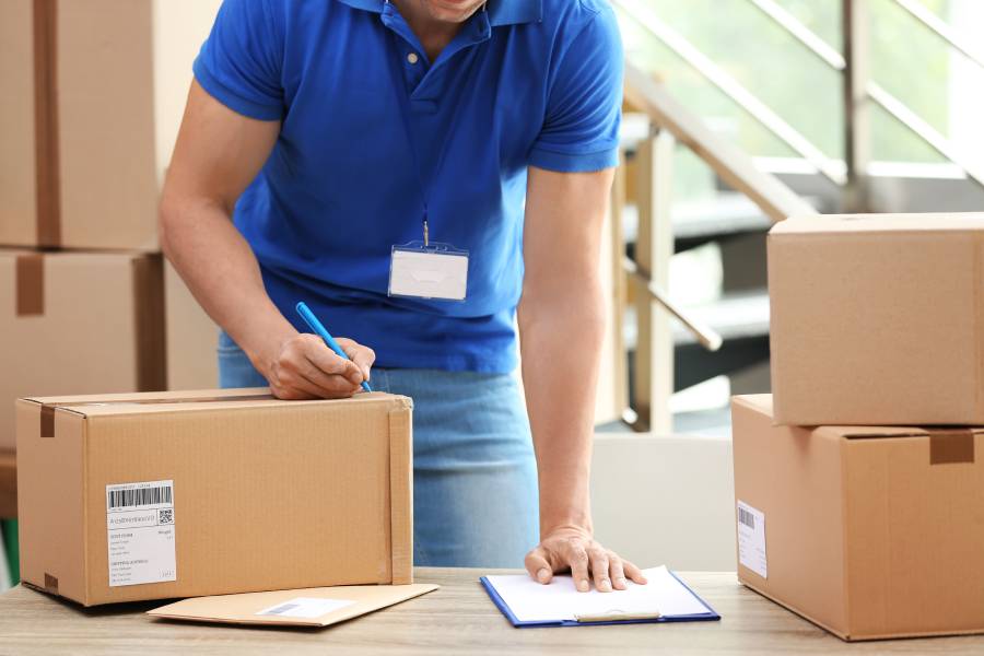 Operador de almacén revisando paquetes con etiquetas de envío, ya que vender en Coppel requiere logística alineada al SLA del canal 
