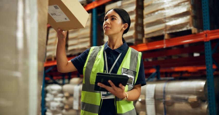Trabajadora de almacén revisando paquete con tablet en operación logística para vender en Falabella
