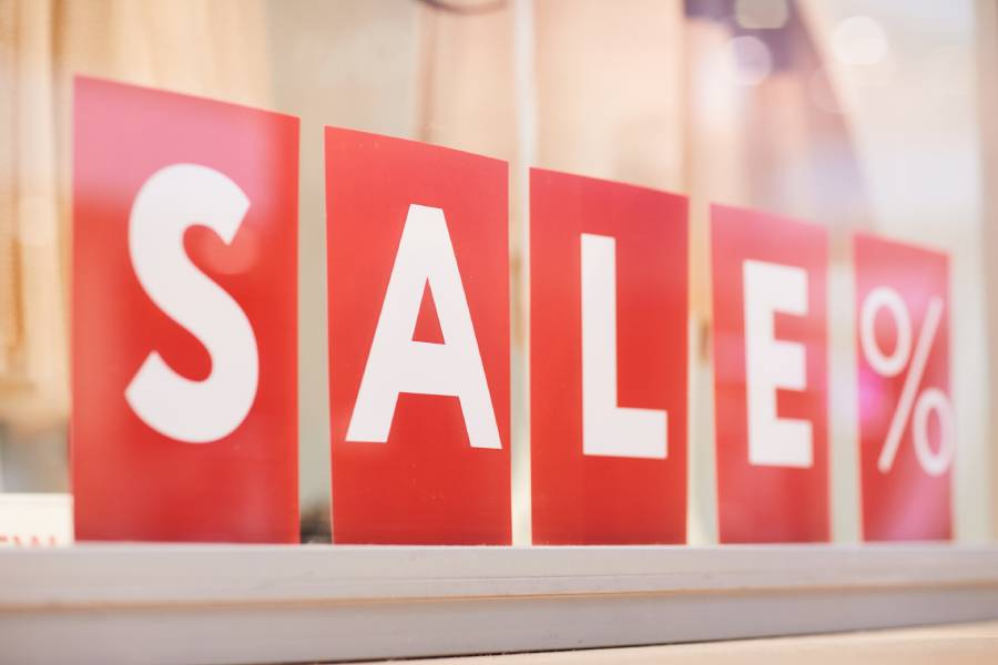 Carteles rojos con la palabra SALE y símbolo de porcentaje en vitrina de tienda durante el hot sale.