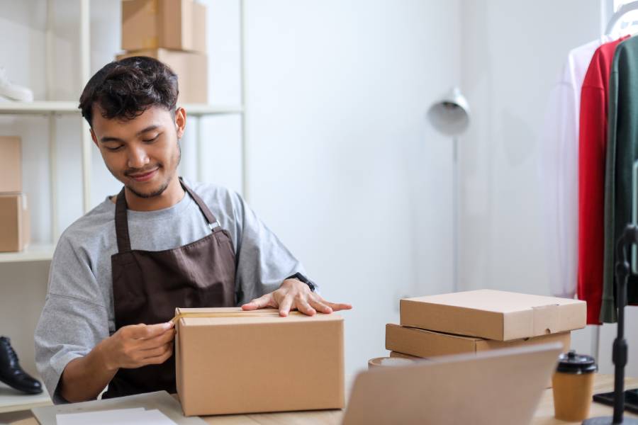 Vendedor preparando cajas con pedidos en la tienda, en representación de quienes comparan ANYTOOLS vs Vambe para gestionar las ventas