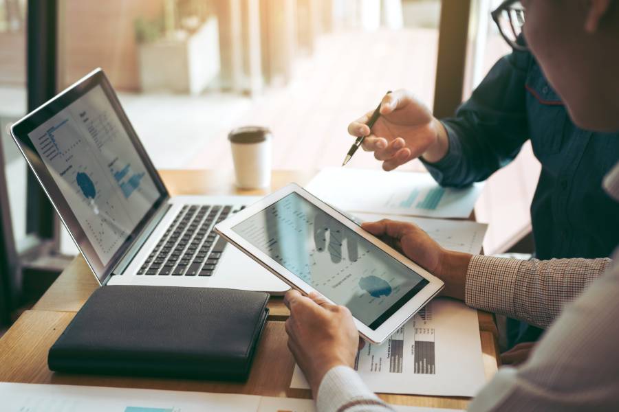 Dos personas revisando datos de integración multicanal en tablet y laptop con reportes y gráficos de ventas 