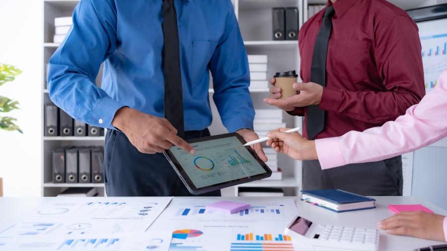 Dos profesionales analizando gráficos de sistema ERP en tablet durante reunión de trabajo en oficina 